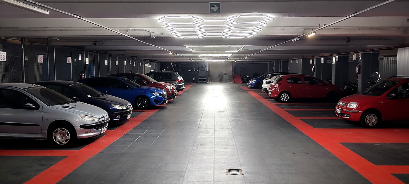 Corridoio del parcheggio custodito, con auto e moto parcheggiate